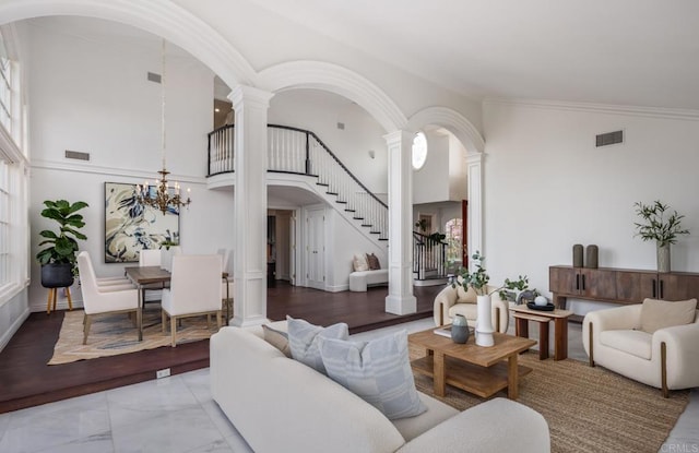 living room featuring an inviting chandelier, high vaulted ceiling, ornamental molding, and decorative columns