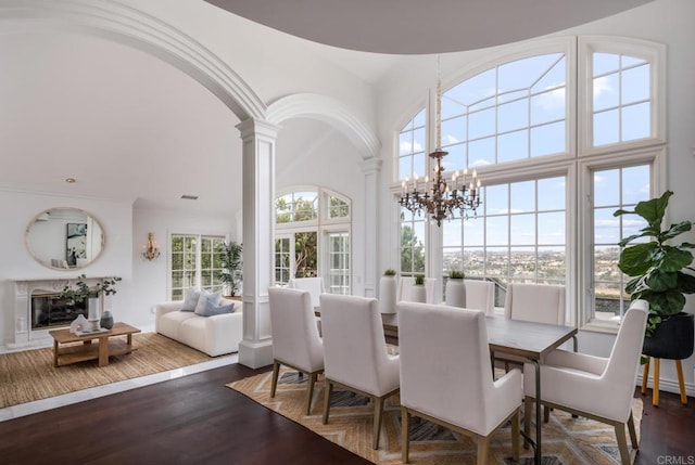 dining room featuring dark wood-type flooring, a wealth of natural light, and ornate columns