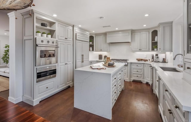 kitchen with a kitchen island, dark hardwood / wood-style floors, sink, light stone counters, and custom range hood