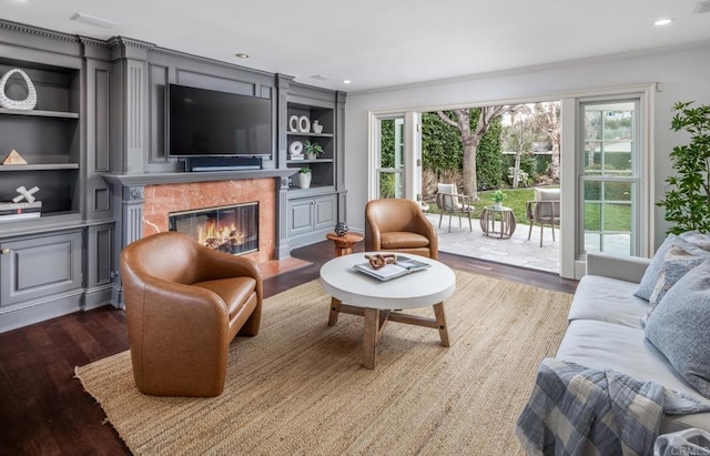 living room with dark wood-type flooring, ornamental molding, a premium fireplace, and built in features