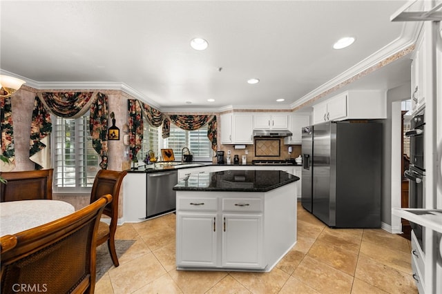 kitchen featuring sink, appliances with stainless steel finishes, white cabinetry, a center island, and dark stone counters