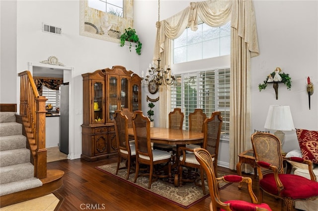 dining room with a high ceiling, dark wood-type flooring, and a notable chandelier