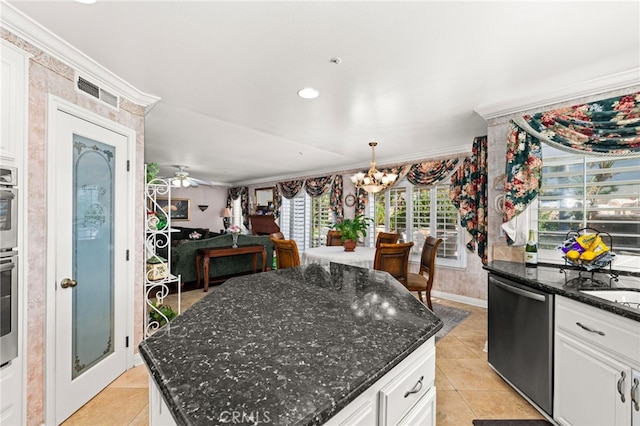 kitchen with pendant lighting, white cabinetry, stainless steel appliances, a center island, and dark stone counters