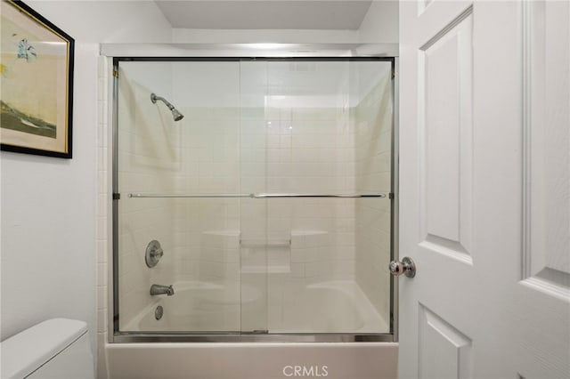 bathroom with bath / shower combo with glass door and toilet