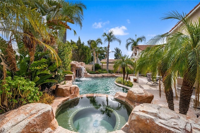 view of swimming pool featuring pool water feature and an in ground hot tub