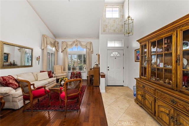 foyer entrance with a healthy amount of sunlight, an inviting chandelier, high vaulted ceiling, and light wood-type flooring