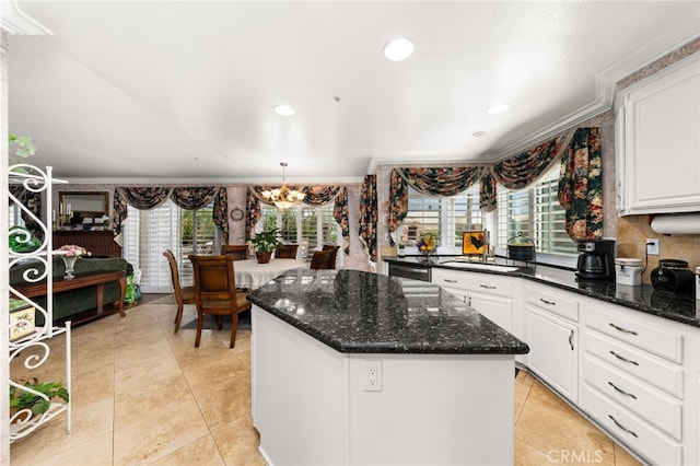 kitchen featuring a center island, a chandelier, pendant lighting, dark stone counters, and white cabinets