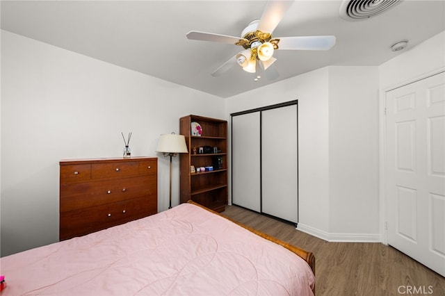 bedroom with wood-type flooring, ceiling fan, and a closet