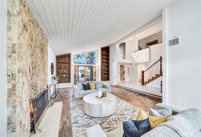 living area with built in shelves, a premium fireplace, wood ceiling, wood finished floors, and stairs