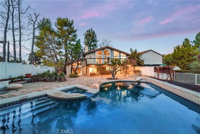 view of pool featuring a diving board, a patio, a fenced backyard, and a pool with connected hot tub