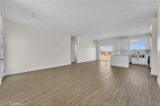 unfurnished living room featuring sink and light wood-type flooring