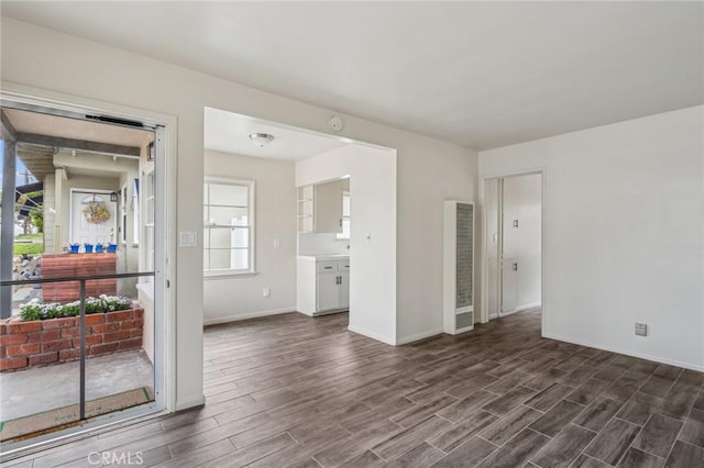 unfurnished room with dark wood-style flooring and baseboards