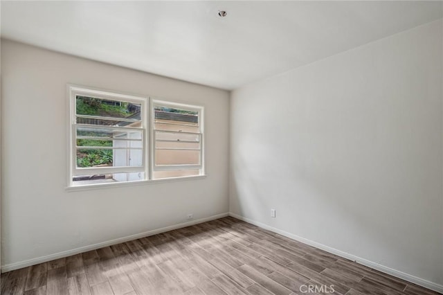 unfurnished room with baseboards and wood finished floors