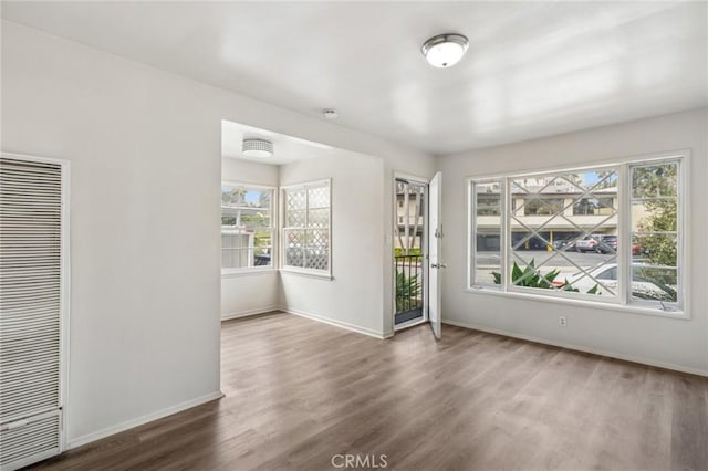 spare room with baseboards, a heating unit, and wood finished floors