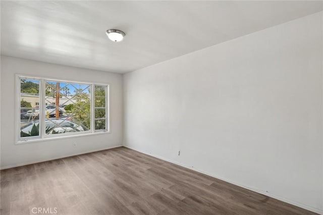 spare room featuring wood finished floors and baseboards