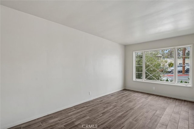 empty room featuring wood finished floors and baseboards