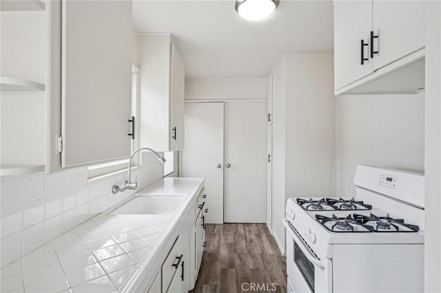kitchen featuring a sink, dark wood-style flooring, white cabinetry, white gas range, and tile countertops