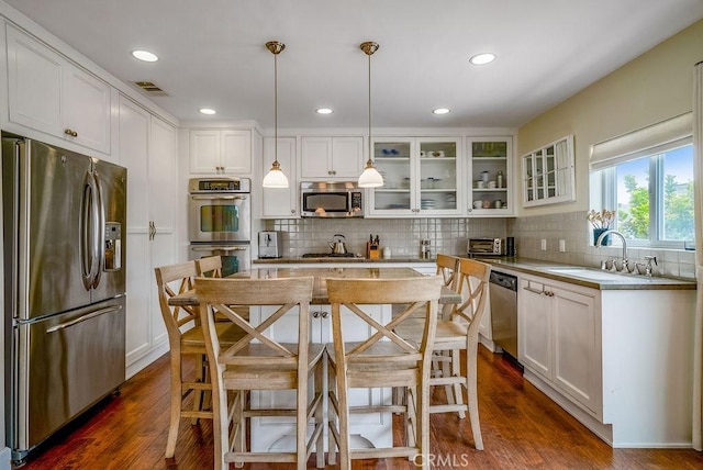 kitchen with visible vents, glass insert cabinets, white cabinets, stainless steel appliances, and a sink