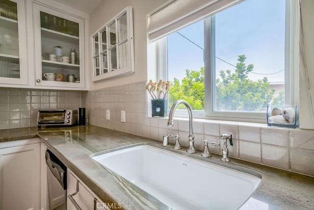 kitchen with white cabinetry, glass insert cabinets, backsplash, and a sink