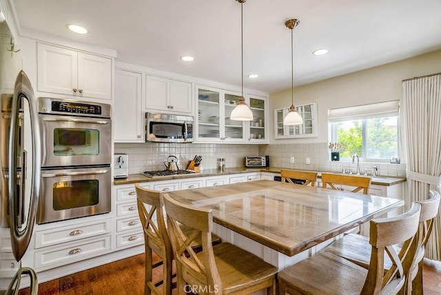 kitchen featuring stainless steel appliances, white cabinetry, tasteful backsplash, and light stone counters