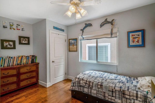 bedroom with a ceiling fan, wood finished floors, and baseboards