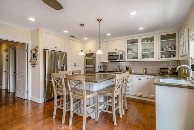 kitchen featuring decorative light fixtures, sink, decorative backsplash, a center island, and stainless steel appliances