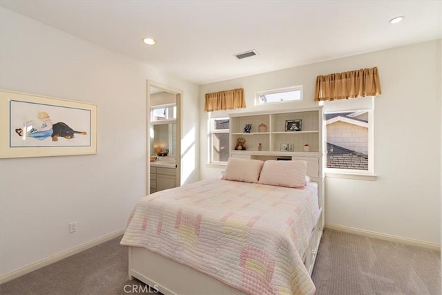 bedroom with connected bathroom and carpet flooring