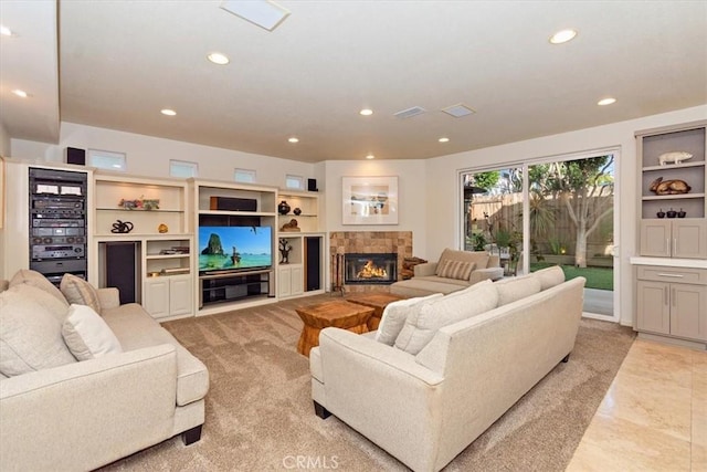 living room featuring a tile fireplace and built in shelves