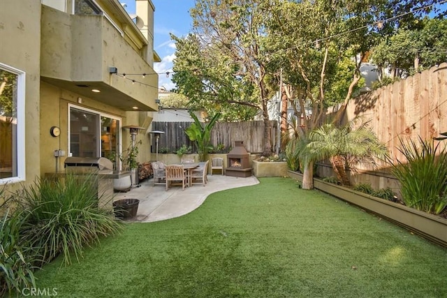 view of yard with exterior fireplace and a patio area