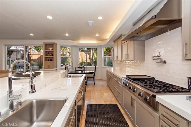 kitchen with tasteful backsplash, stainless steel gas stovetop, a tray ceiling, and sink