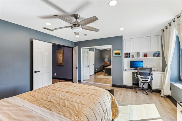 bedroom featuring ceiling fan, built in desk, light wood-type flooring, and a closet