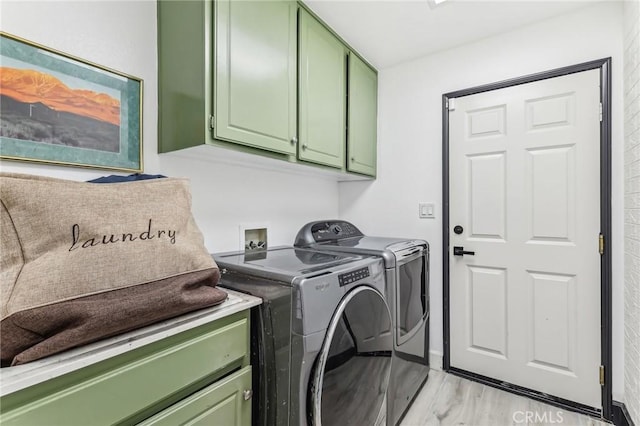 laundry area with independent washer and dryer, light hardwood / wood-style floors, and cabinets