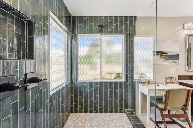 bathroom featuring a tile shower, vanity, and a wealth of natural light