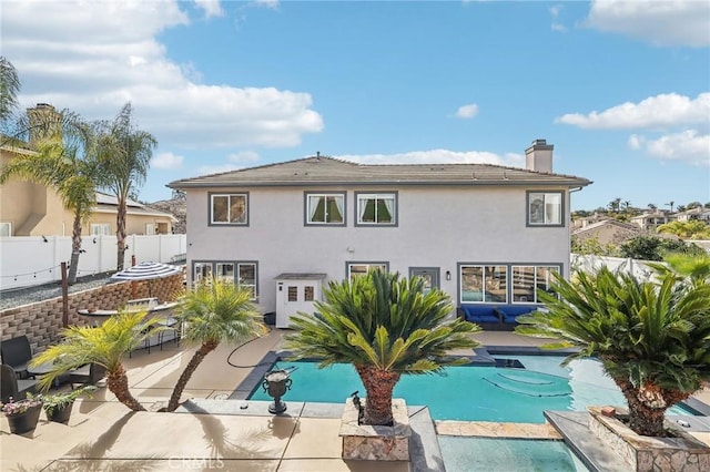 back of property with a fenced in pool and a patio area