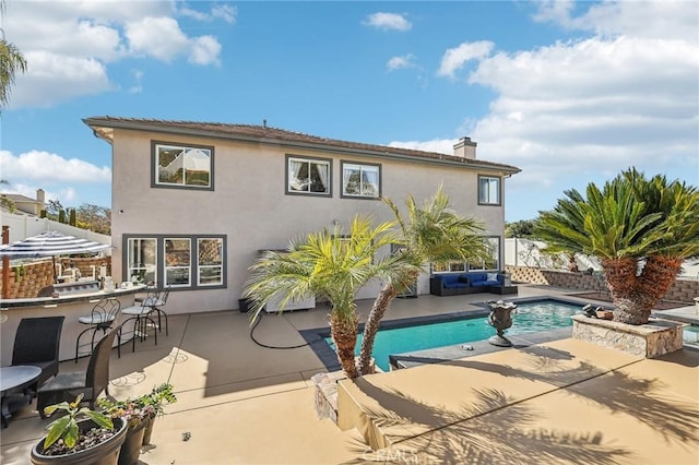 rear view of property with a fenced in pool, a patio, and an outdoor bar