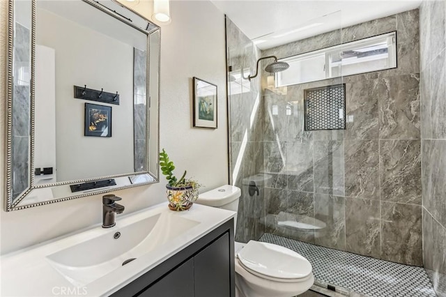 bathroom with vanity, a tile shower, and toilet