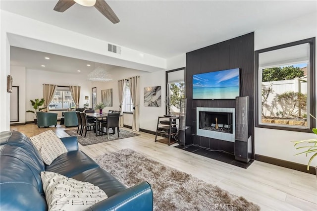 living room with light hardwood / wood-style flooring, a fireplace, and ceiling fan