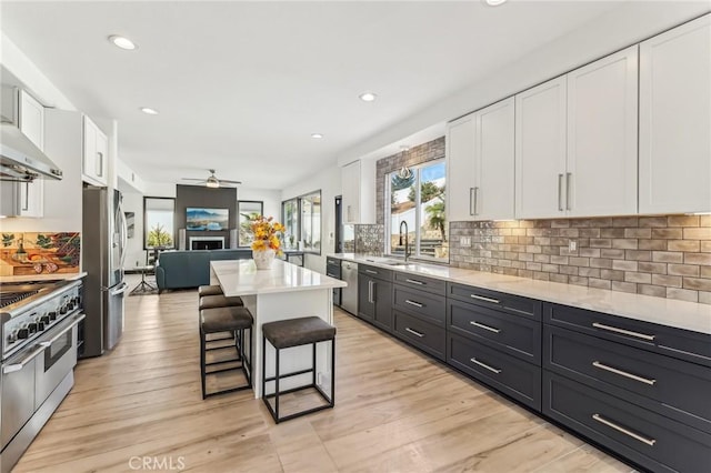 kitchen with sink, a breakfast bar, appliances with stainless steel finishes, white cabinetry, and a center island