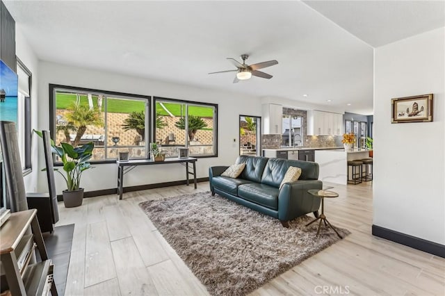 living room with ceiling fan, sink, and light hardwood / wood-style floors