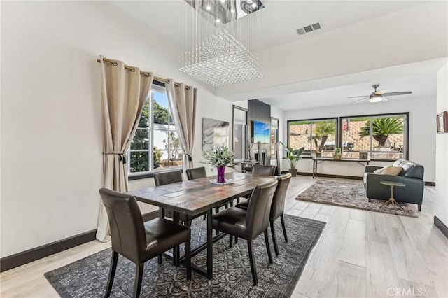 dining room featuring ceiling fan with notable chandelier, a healthy amount of sunlight, and light hardwood / wood-style floors