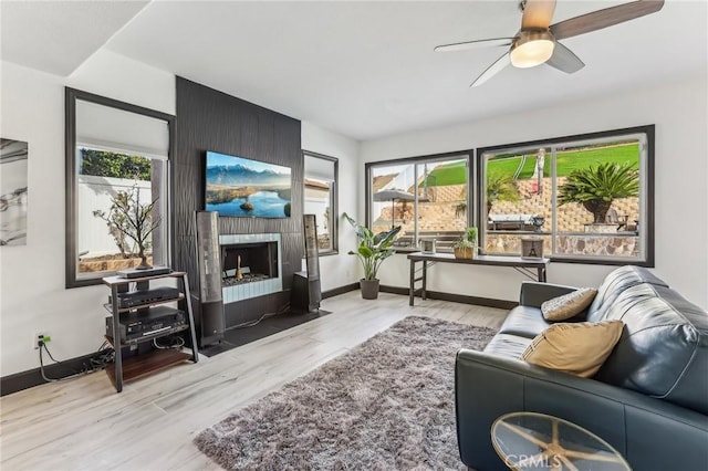 living room with a healthy amount of sunlight, light wood-type flooring, ceiling fan, and a fireplace