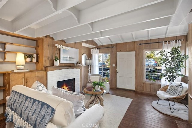 living room featuring hardwood / wood-style floors, vaulted ceiling with beams, wood walls, and a brick fireplace