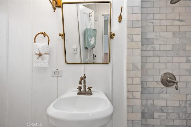 bathroom with a tile shower and a sink