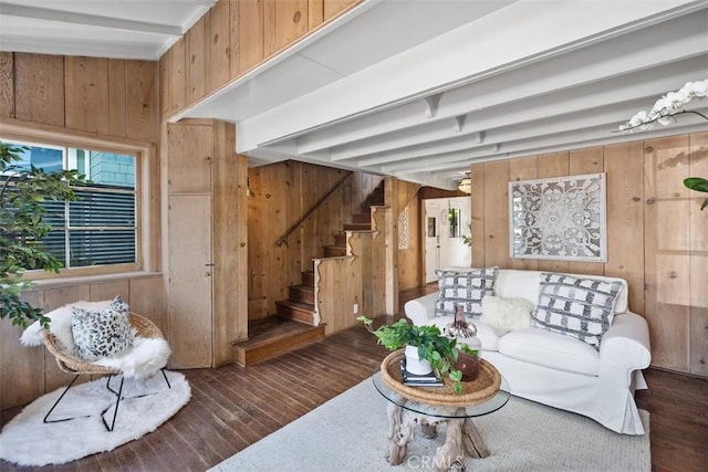 living room featuring hardwood / wood-style floors, wood walls, stairway, and beamed ceiling