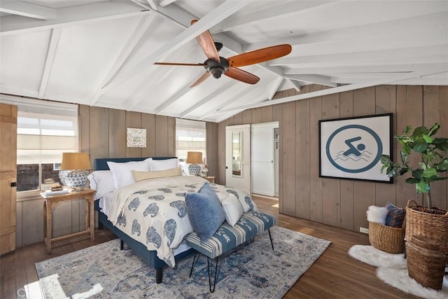 bedroom with lofted ceiling with beams, wood finished floors, and wooden walls