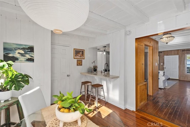 dining room with hardwood / wood-style flooring, baseboards, and beam ceiling