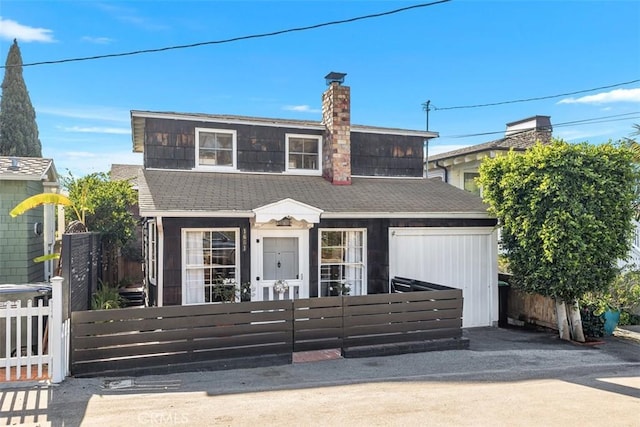 view of front facade with a shingled roof, a fenced front yard, and a chimney
