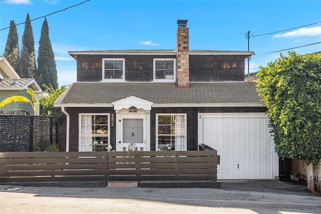 view of front of property featuring a shingled roof, a chimney, and a fenced front yard