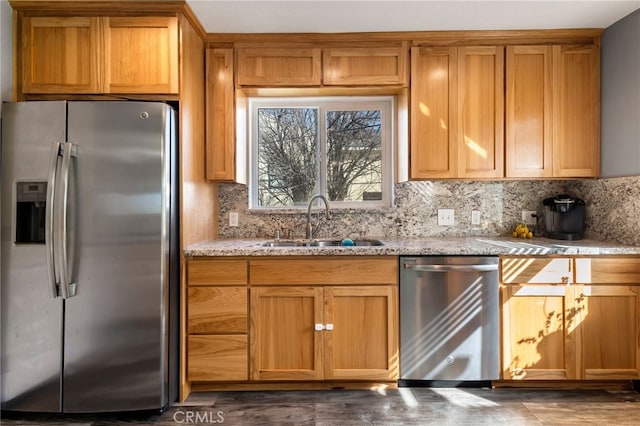 kitchen with stainless steel appliances, a sink, light stone counters, and decorative backsplash