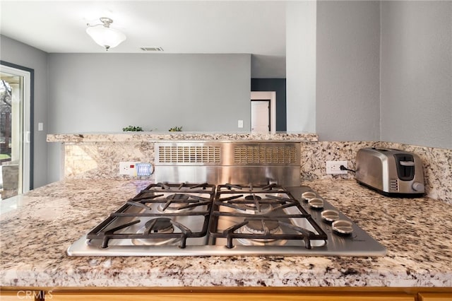 interior details with gas stovetop and light stone countertops